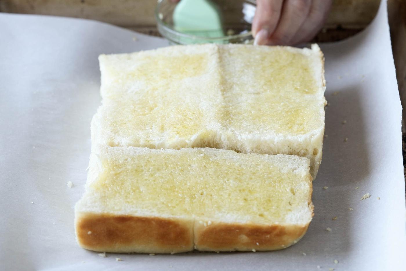 brushing olive oil onto the slider buns