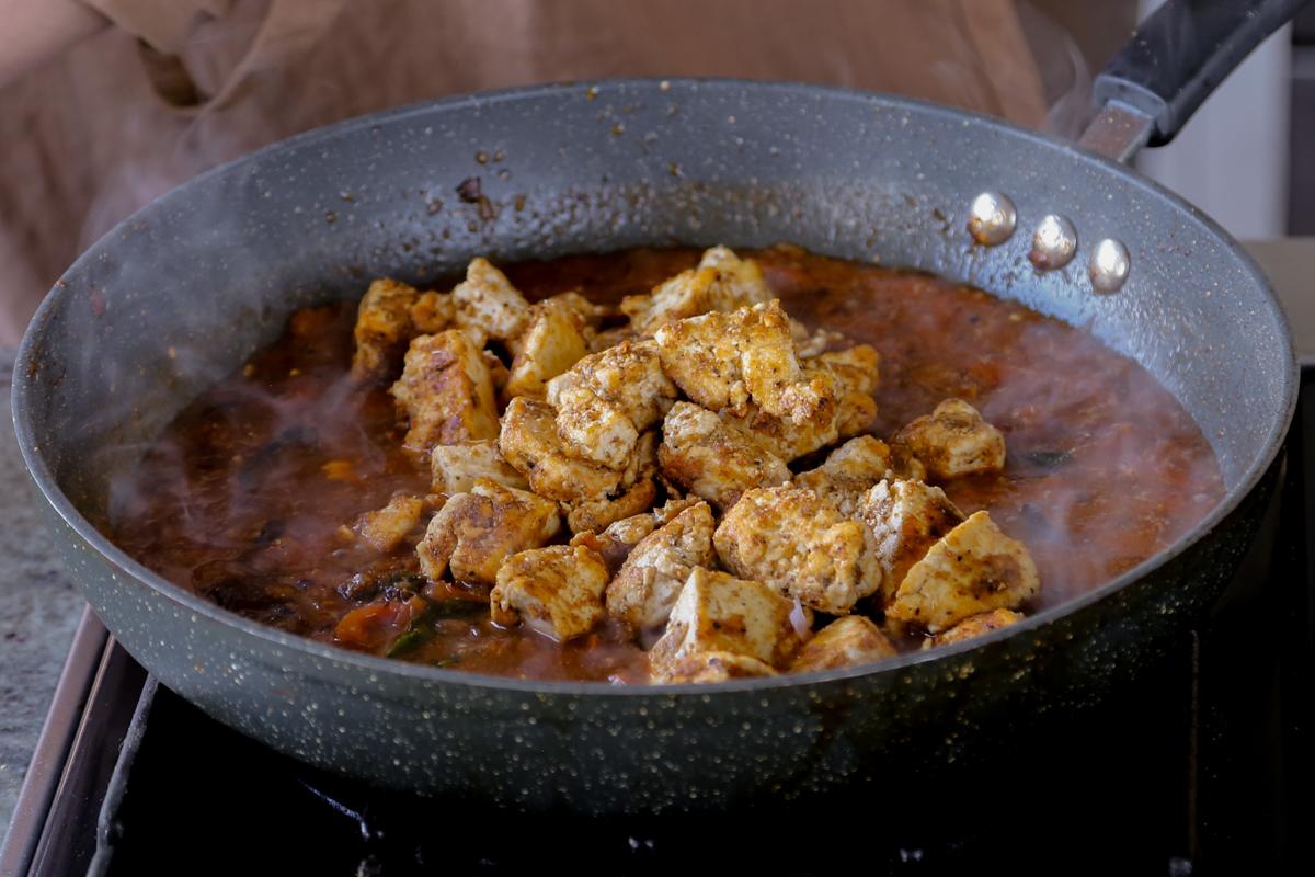 adding crisped up tofu to the Chettinad pepper chicken sauce in the pan