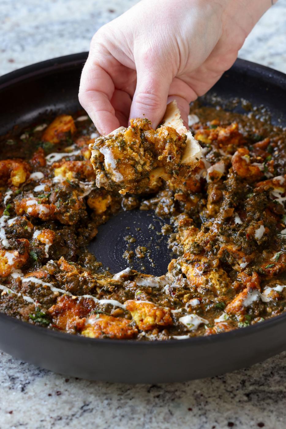 dipping flatbread into chicken saagwala