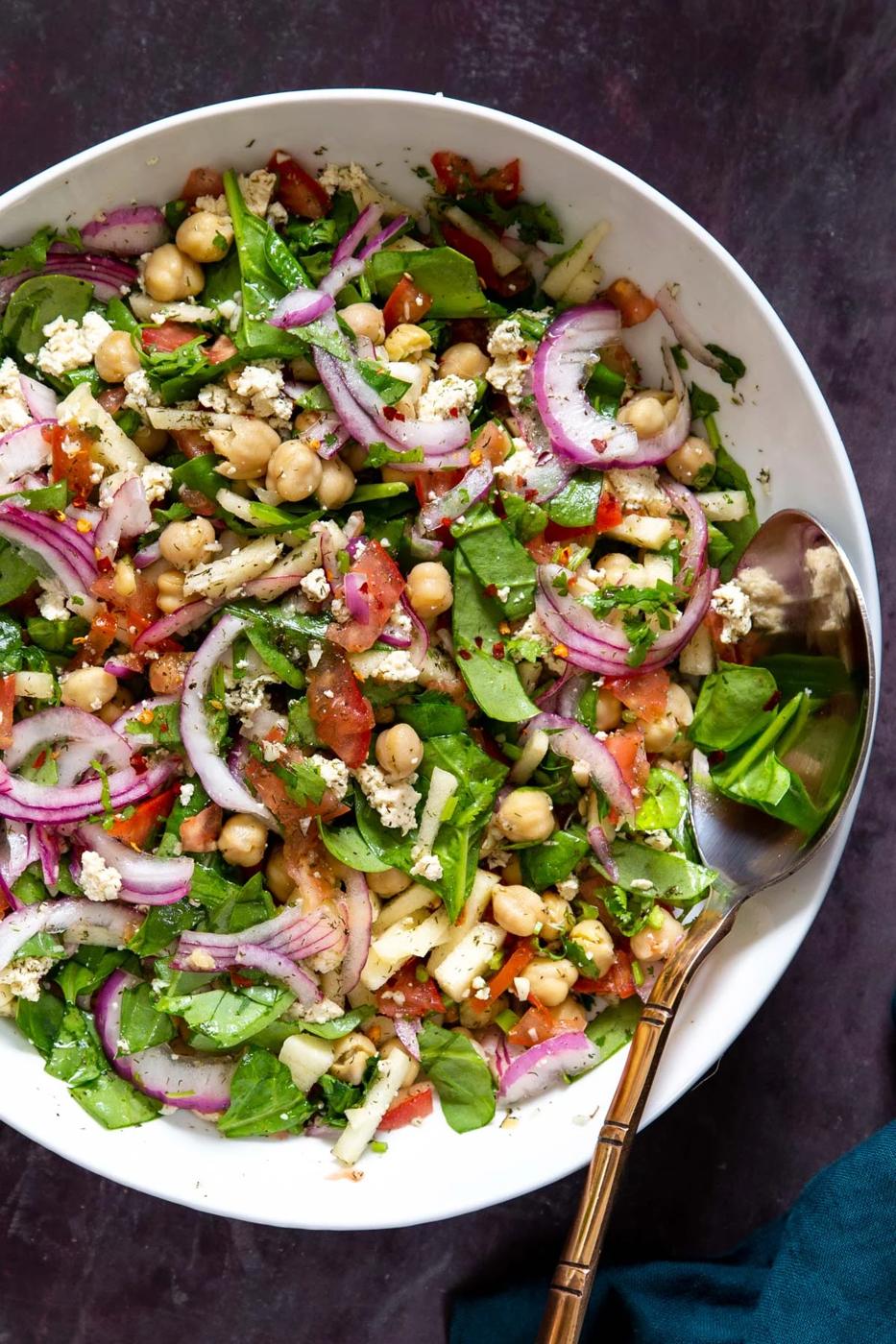 vegan chickpea salad with lemon dill dressing in a white bowl with a spoon on the side