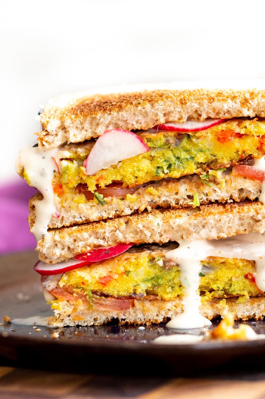 stacked vegan breakfast sandwich filled with chickpea flour pancakes and vegetables