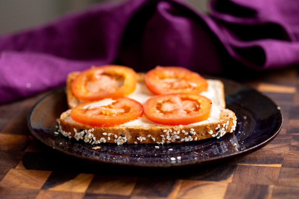 a slice of bread being topped with ranch and tomatoes