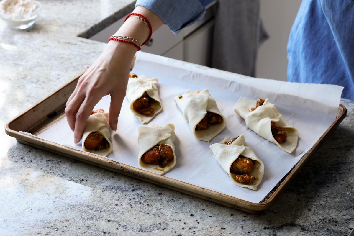 placing filled tofu puff pastries on the baking sheet