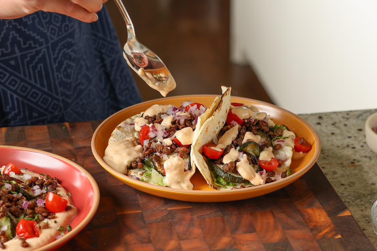 assembling the chipotle whipped tofu, roasted zucchini, and crispy lentils tacos