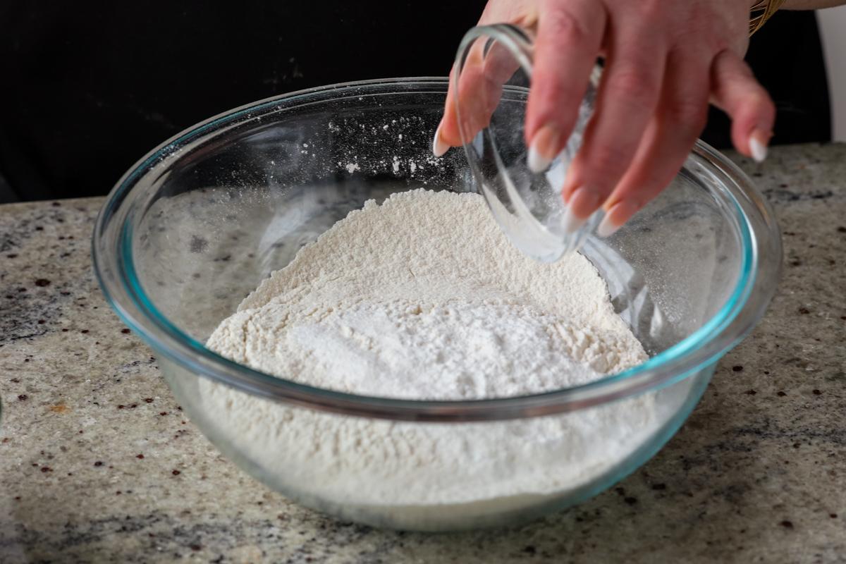 adding dry ingredients to a bowl