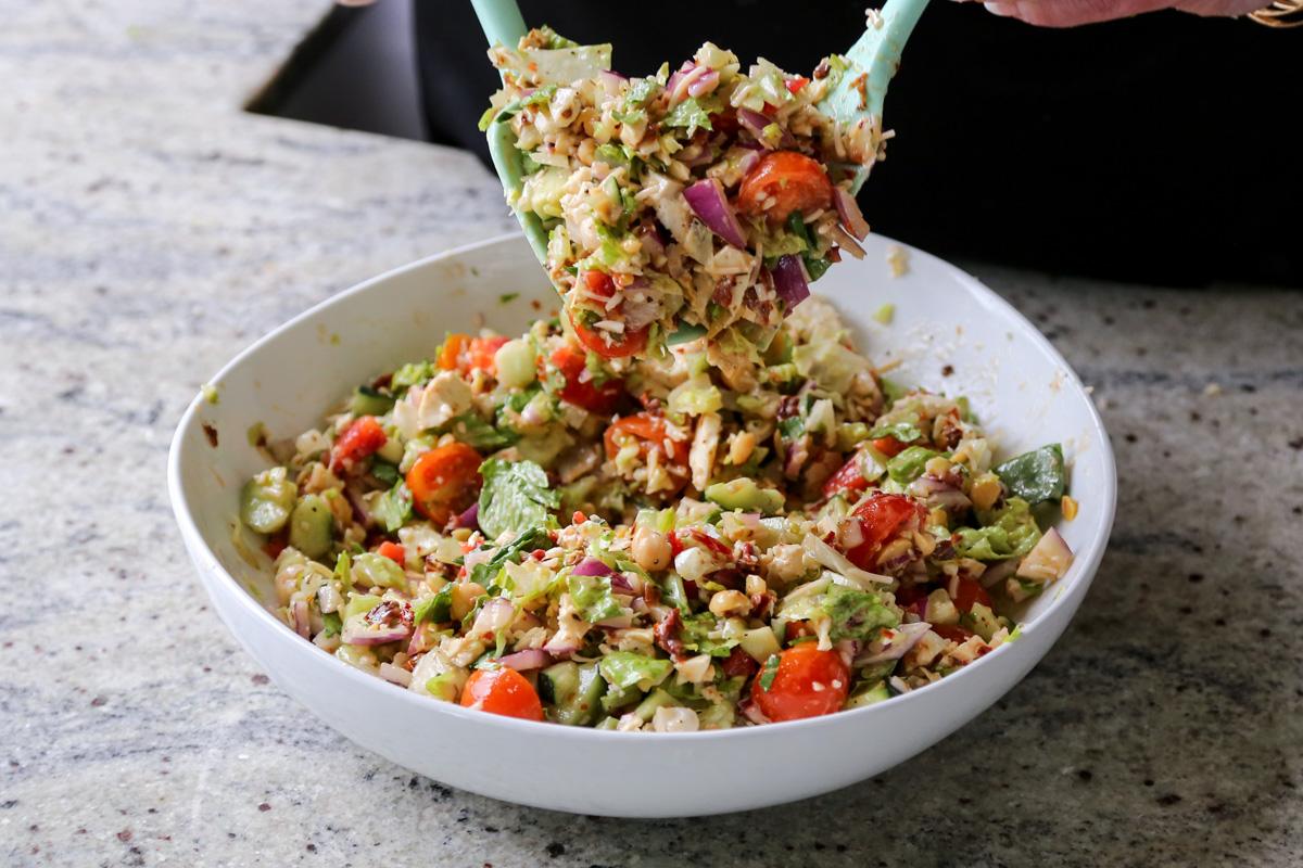 tossing the chopped Italian salad together with the dressing