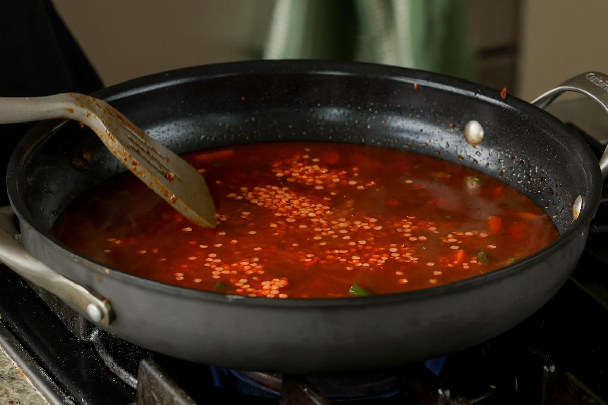 adding red lentils to the pan
