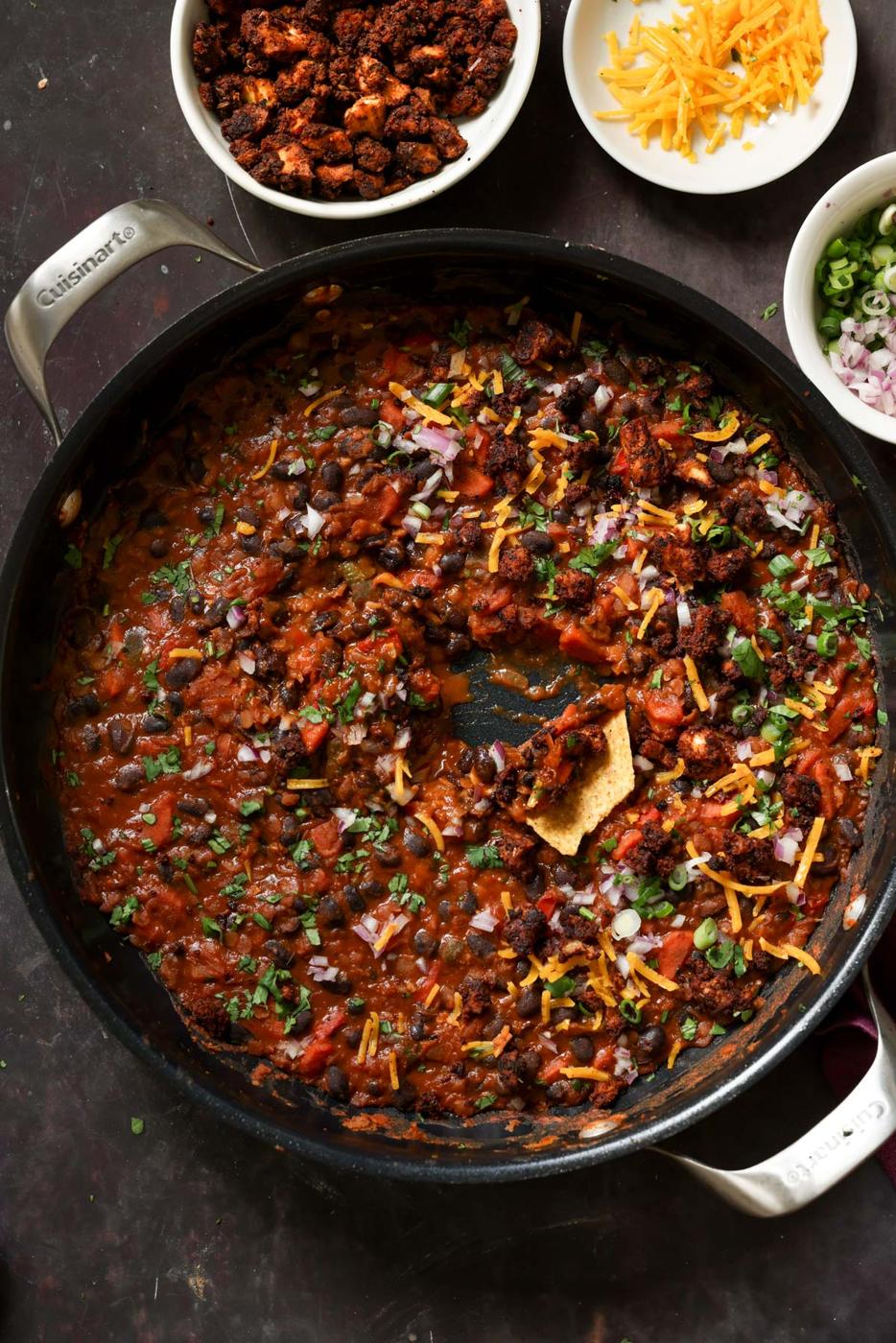 cooked beans in the pan after adding toppings and dipping a tortilla chip
