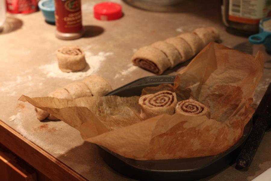 unbaked vegan cinnamon rolls being placed into a round cake pan