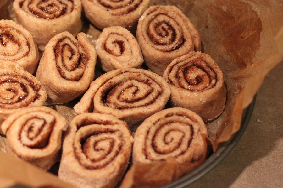 vegan cinnamon rolls proofing in a round parchment-lined cake pan