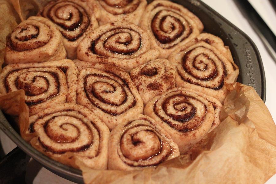 risen vegan cinnamon buns in a round cake pan ready to be baked