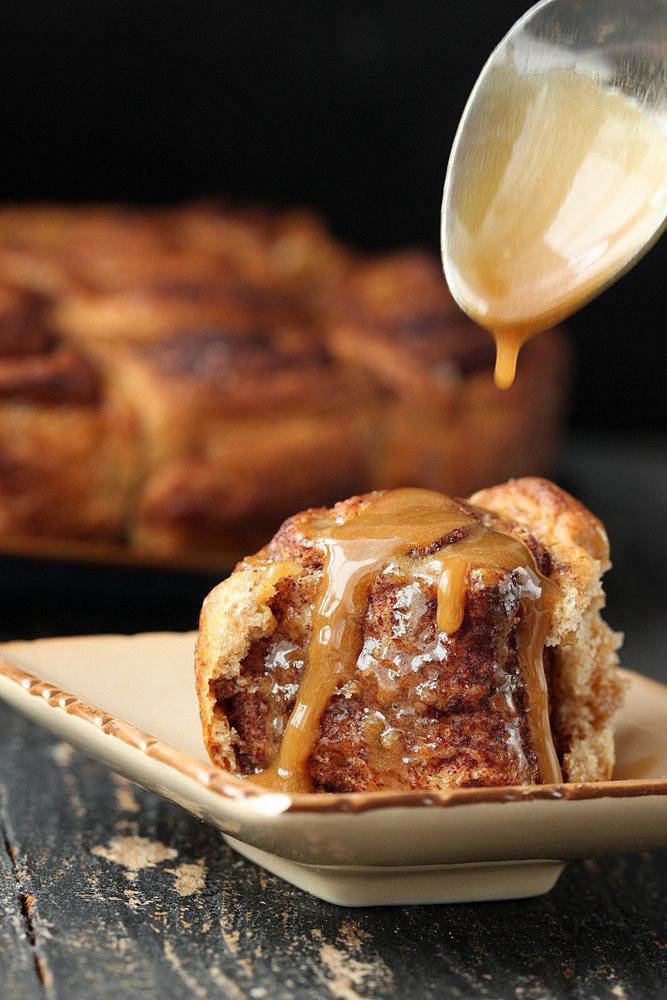 maple coffee icing being drizzled on top of vegan cinnamon rolls