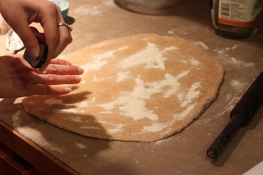granulated sugar being sprinkled on rolled out cinnamon roll dough