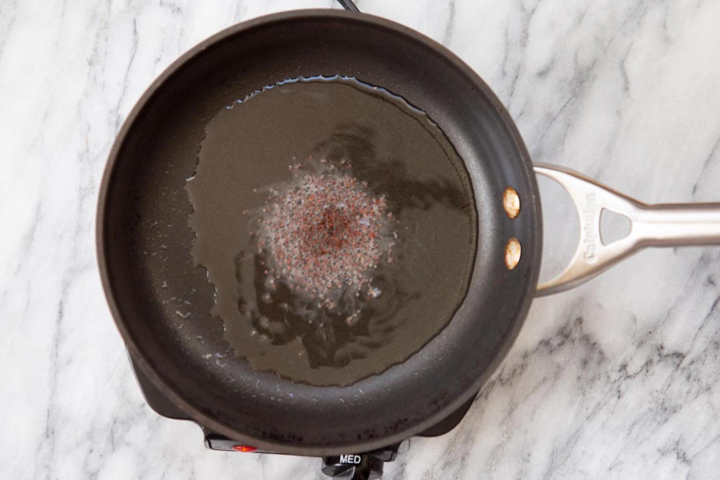 frying mustard seeds for the tempering in a black pan