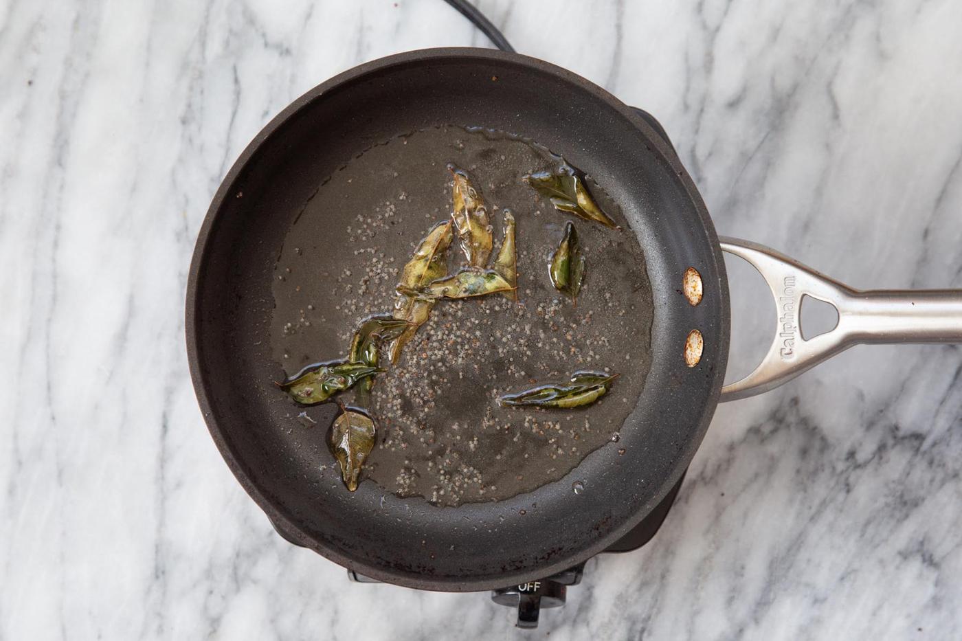 pan of mustard seeds with curry leaves added