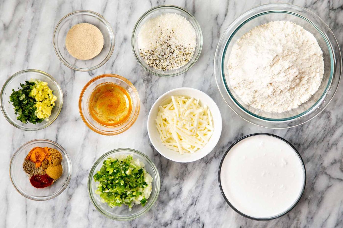 flour, vegan cheese, and other Ingredients in bowls on a marble table