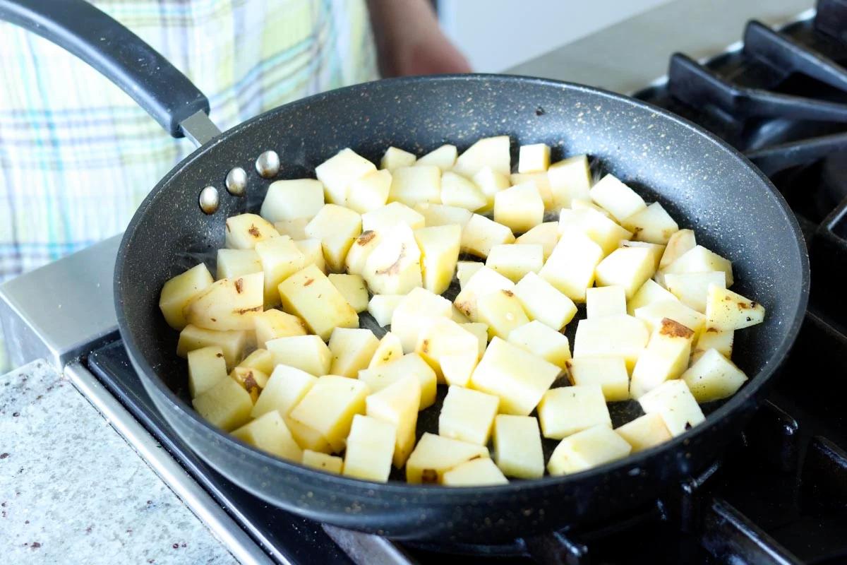 adding potatoes to the pan