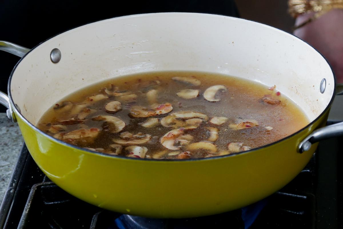 adding broth to the pan