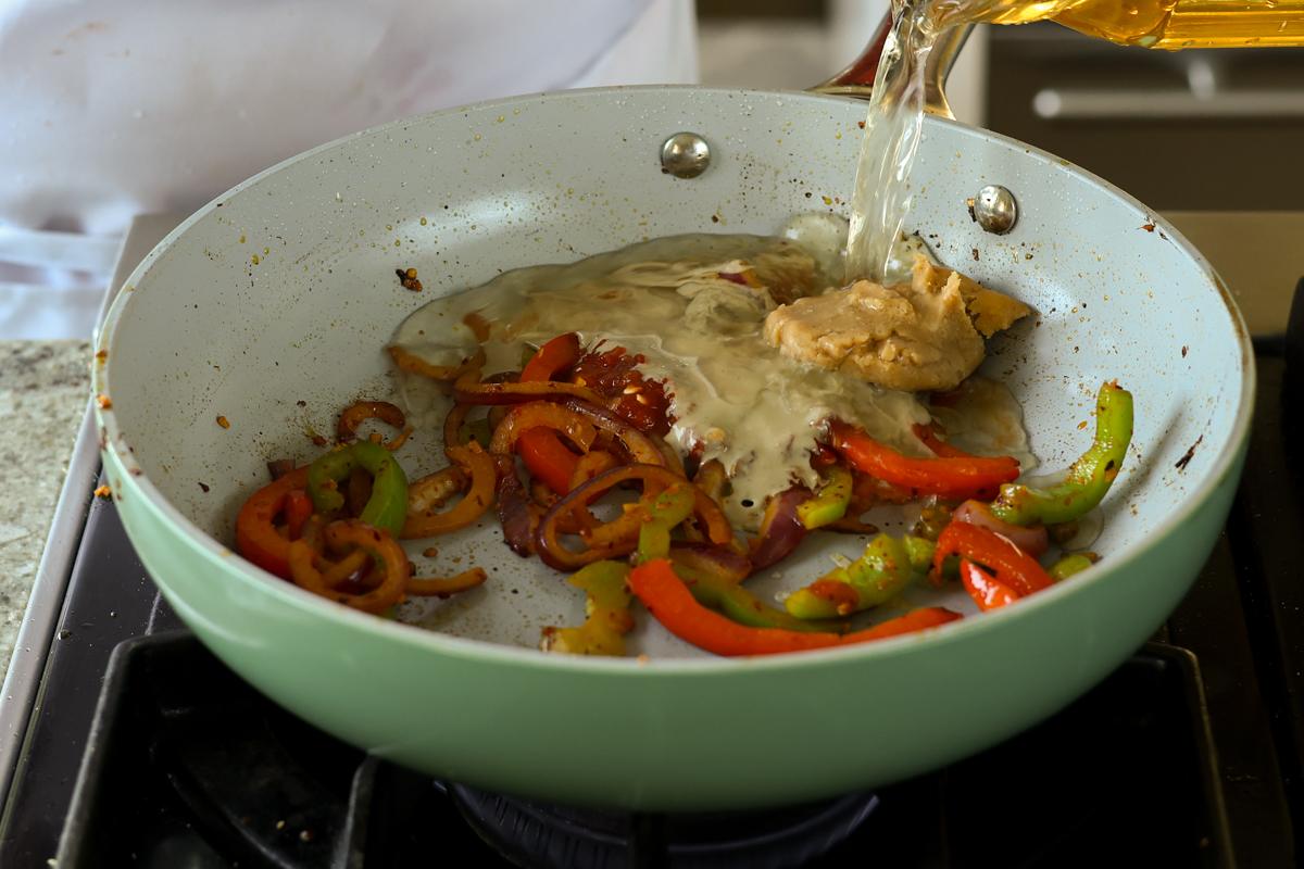 adding more broth ingredients to the pan