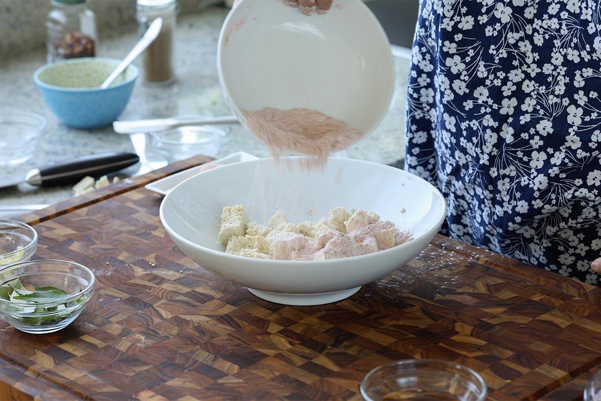 pouring the spice mixture onto the torn tofu