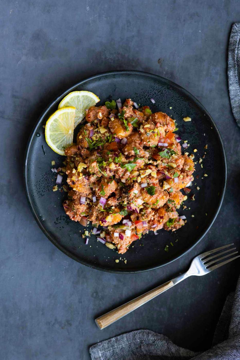 crispy gnocchi muhammara salad on a plate with lemon slices