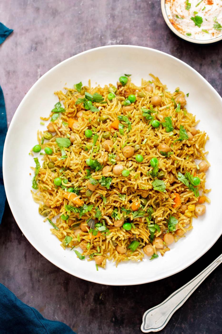 chickpea fried rice with peas and cilantro on a white plate