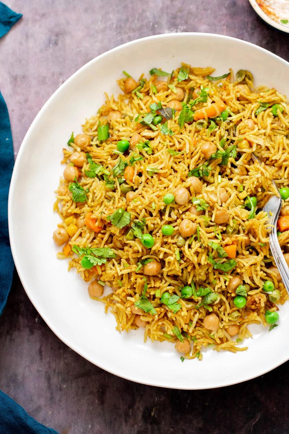 chickpea fried rice on a white plate with a fork