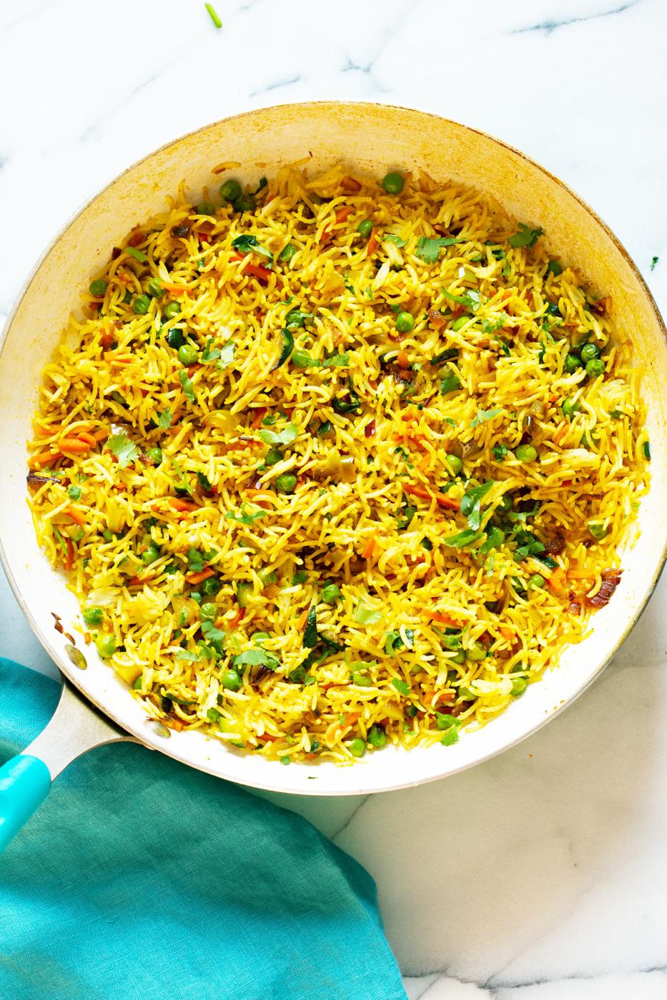 Curry fried rice in a frying pan on a marble work surface