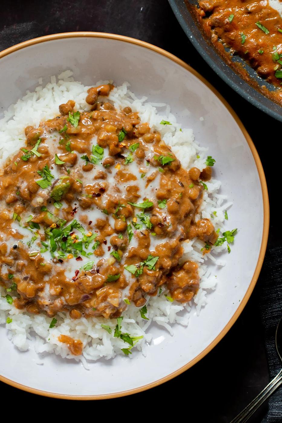 bowl of lasooni dal over rice with cilantro and a swirl of cream
