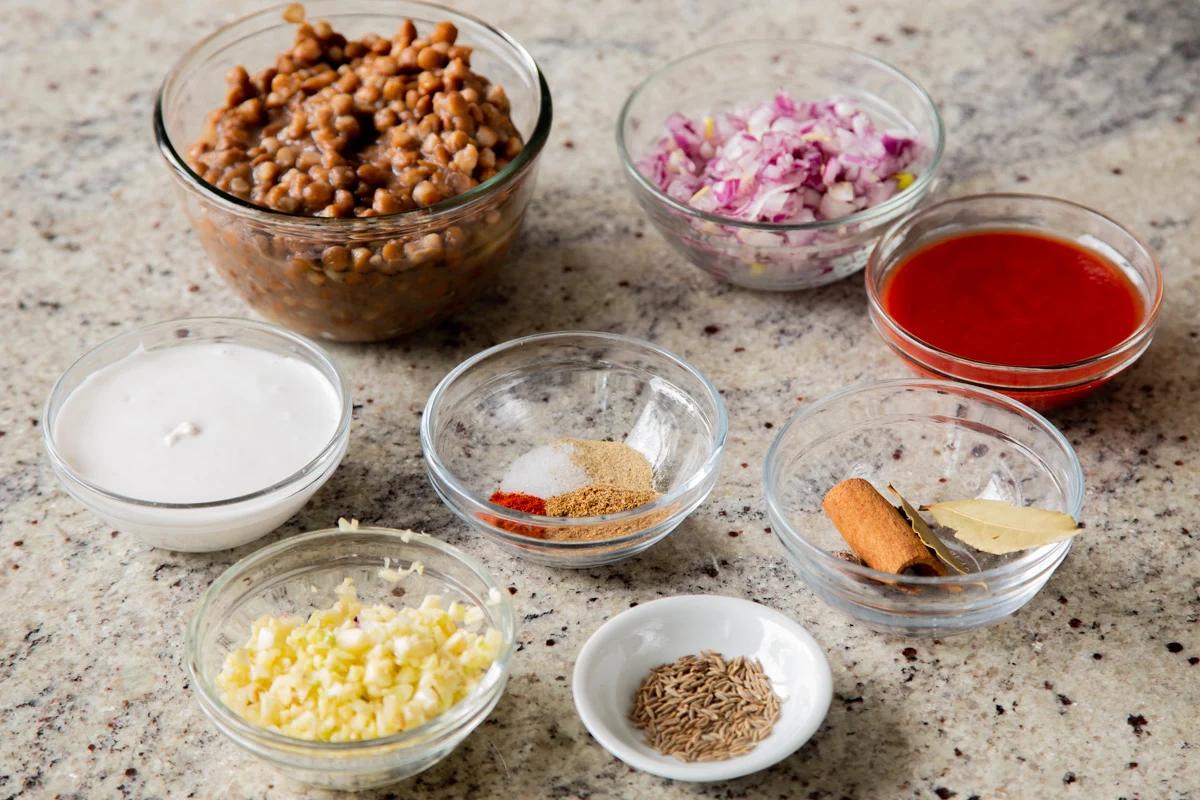 lentils, onion, garlic, and seasonings in bowls on a kitchen counter