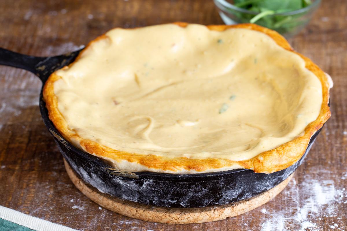 vegan cheese sauce being added to prebaked pretzel pizza crust