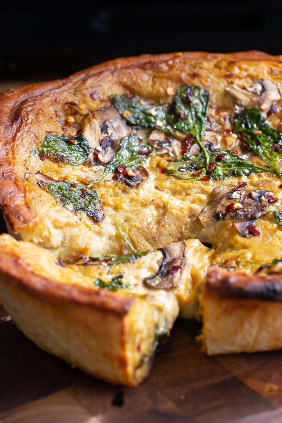vegan deep dish pretzel crust pizza filled with cheese sauce, mushrooms and spinach