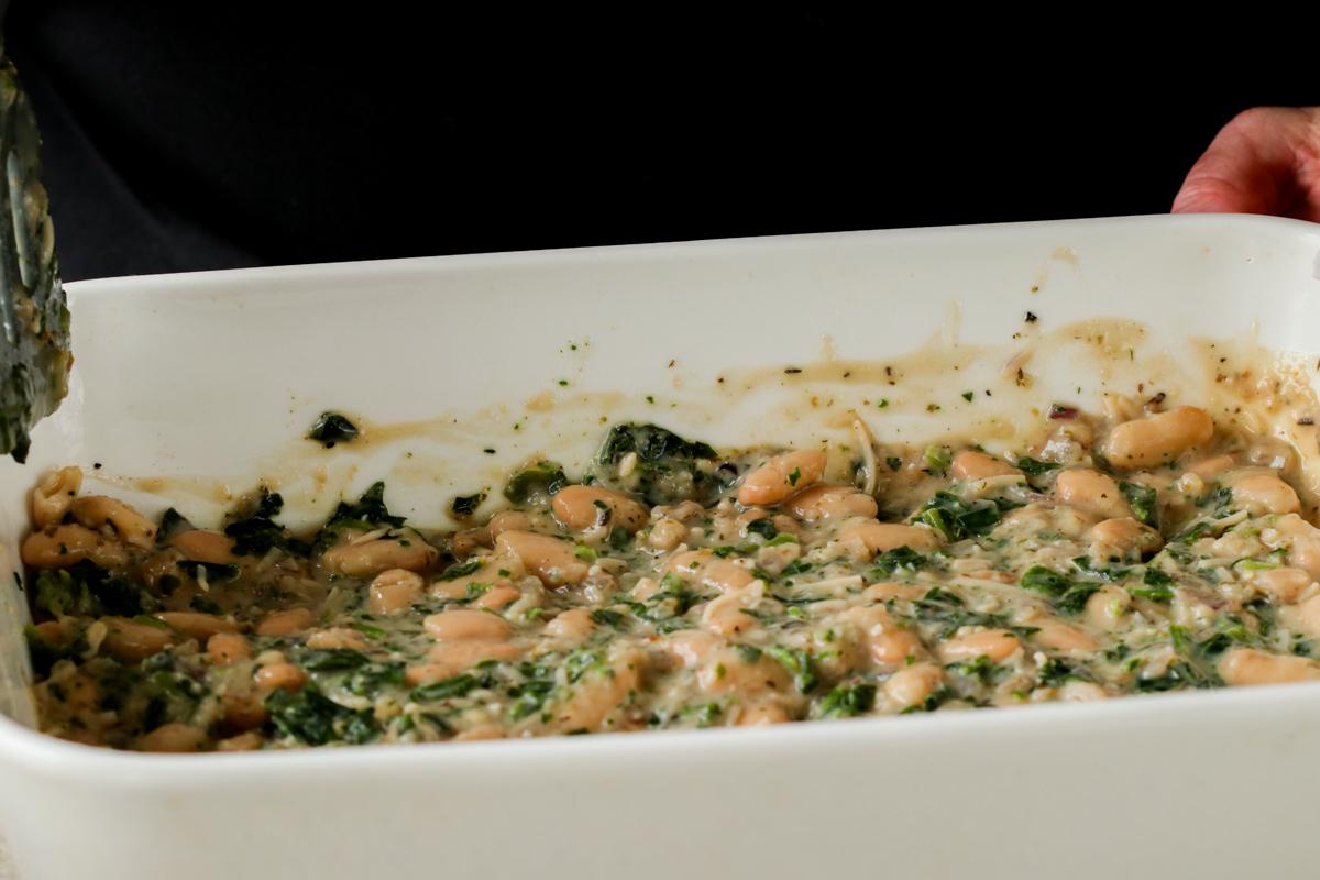 white beans and spinach mixed with white sauce in the casserole dish