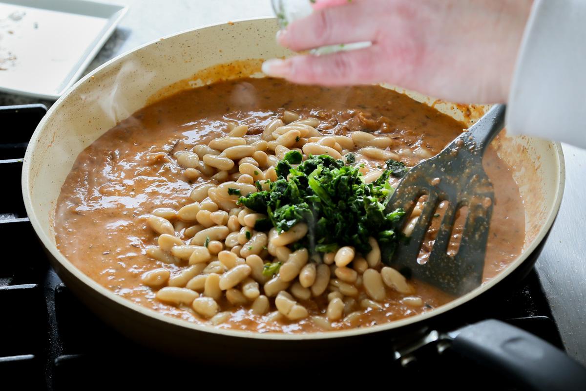 adding white beans and spinach to the pan