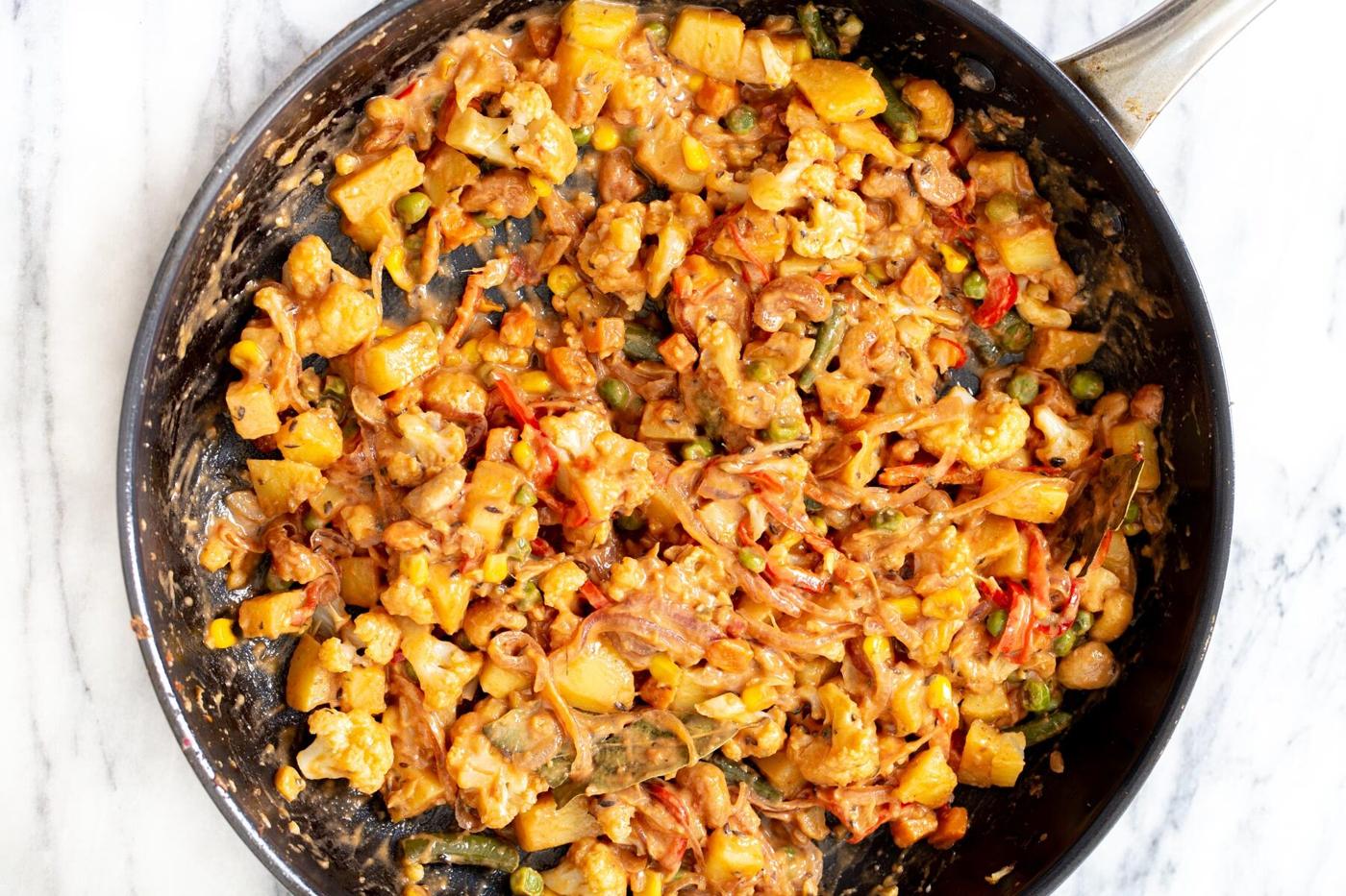 gravy and vegetables being mixed in a sauteeing pan to make diwani handi