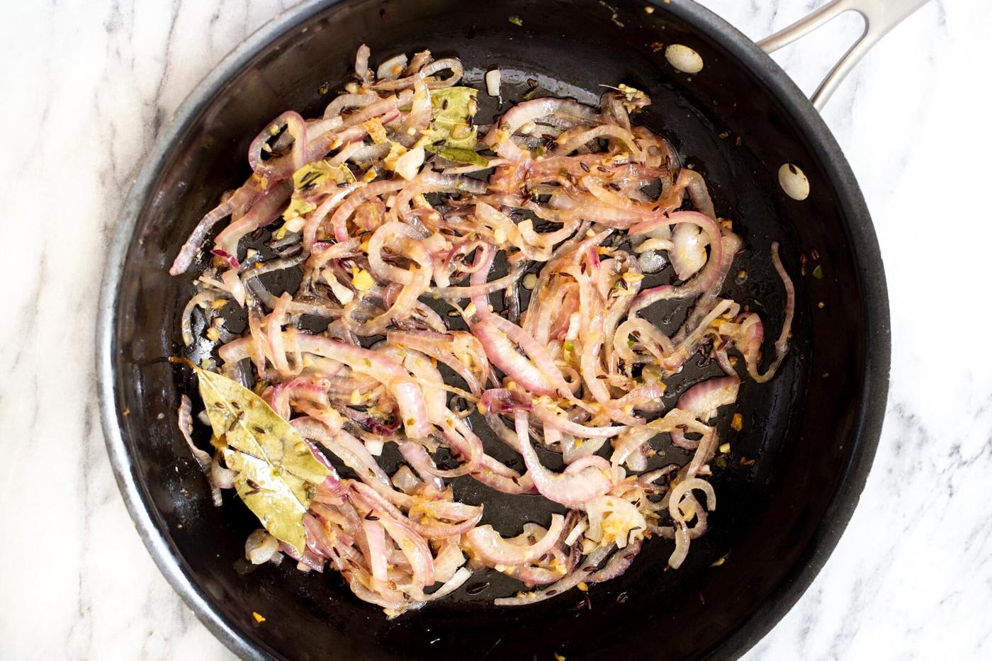 onion and spiced being fried in a pan