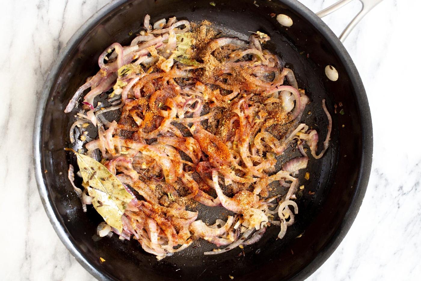 spices being added to sauteed onion