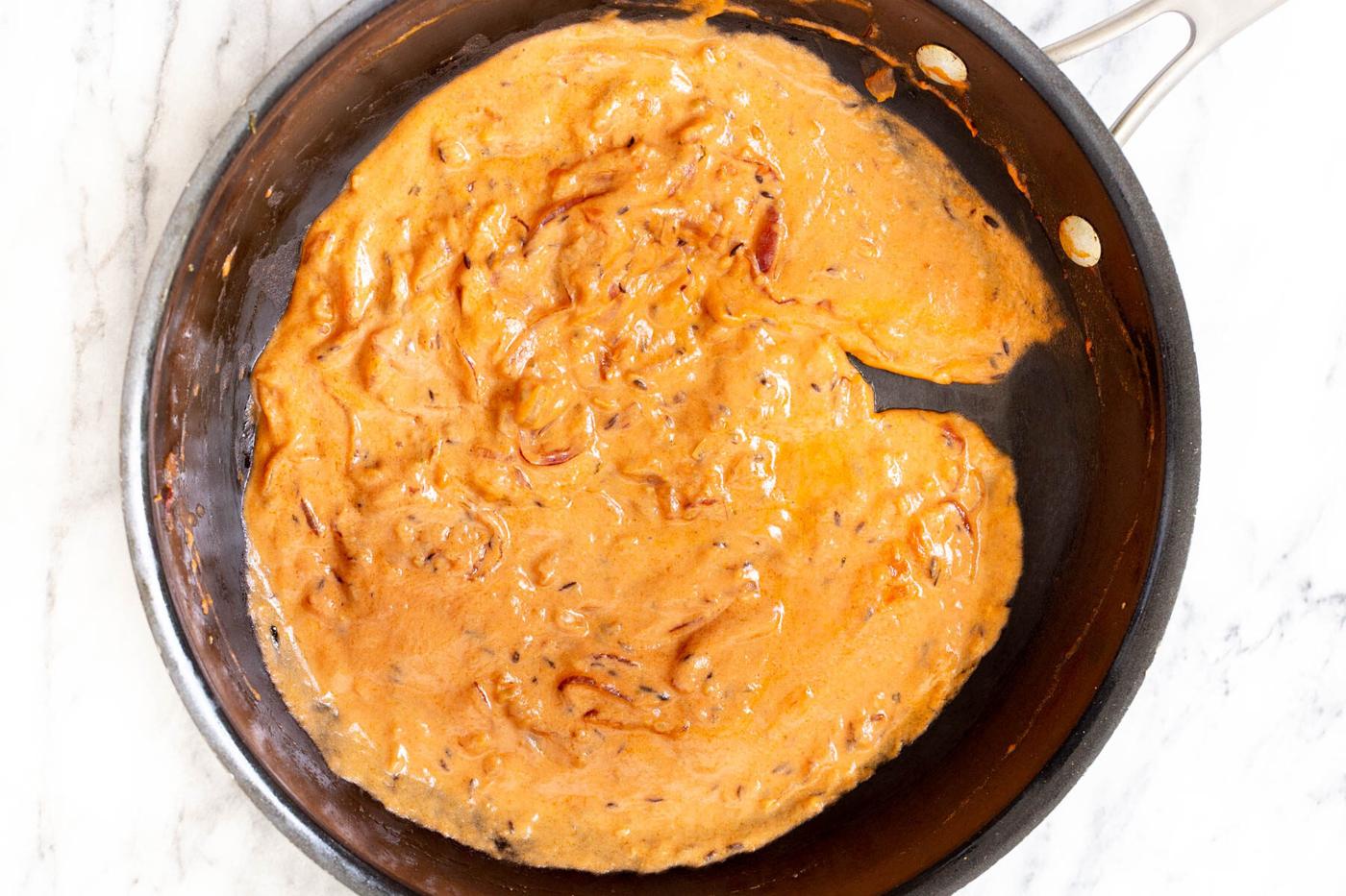non-dairy yogurt being stirred into the Indian tomato gravy