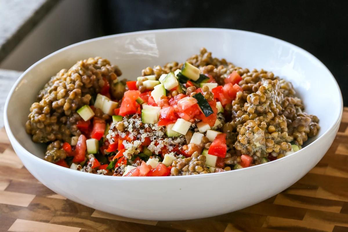 lentils, quinoa, and veggies in a bowl, before mixing