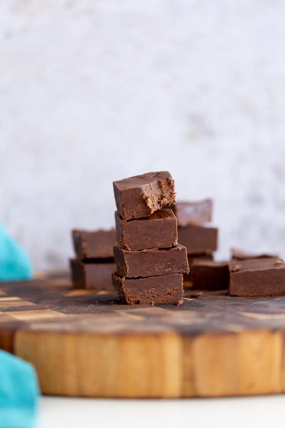 side view of a stach of vegan chocolate fudge on a wooden board
