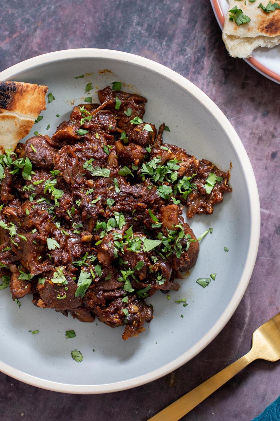 Ethiopian mushroom tibs stir-fry served with a side of bread on a pale blue plate