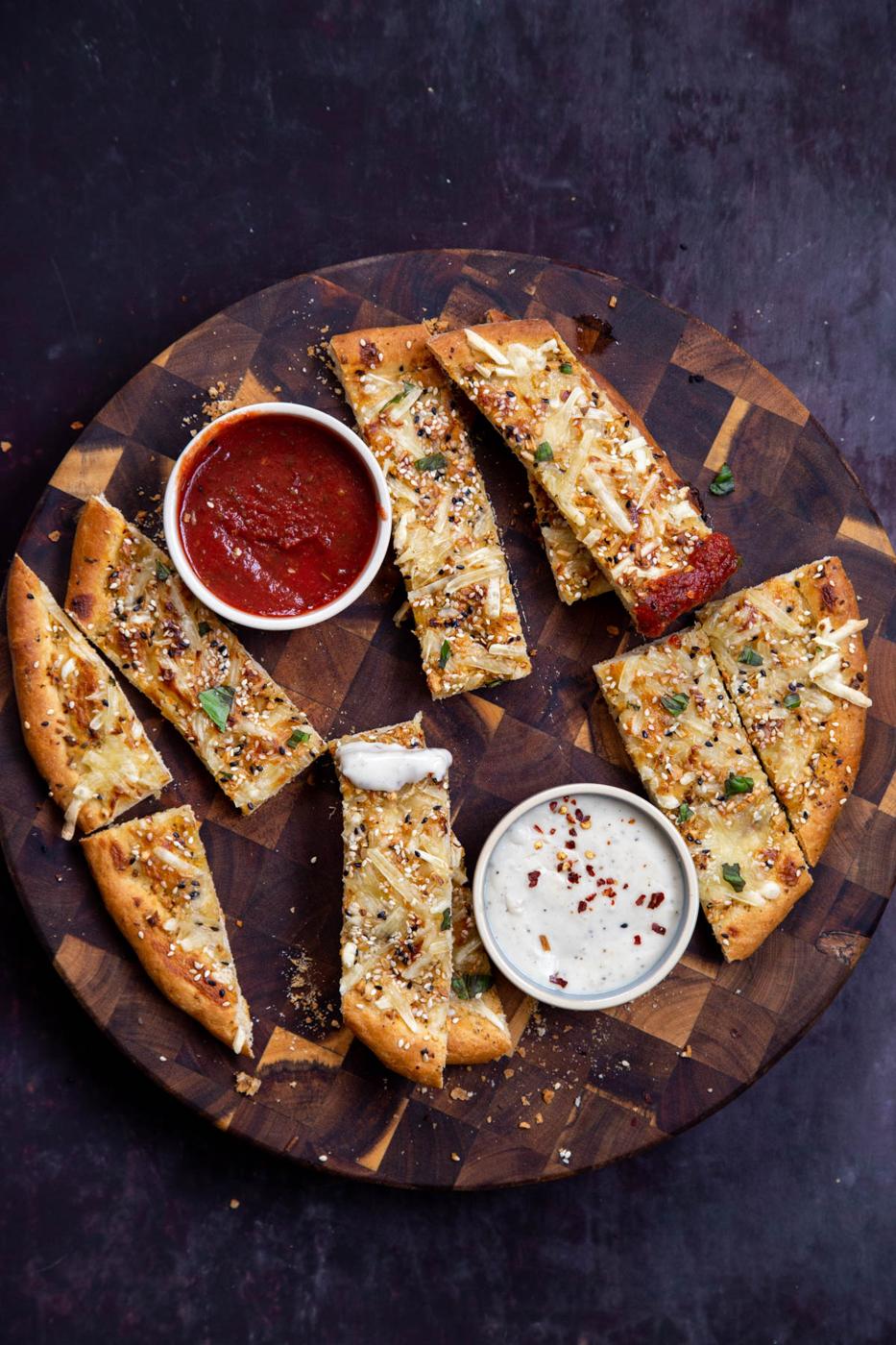 vegan cheesy garlic bread sticks served with dips on a wooden board