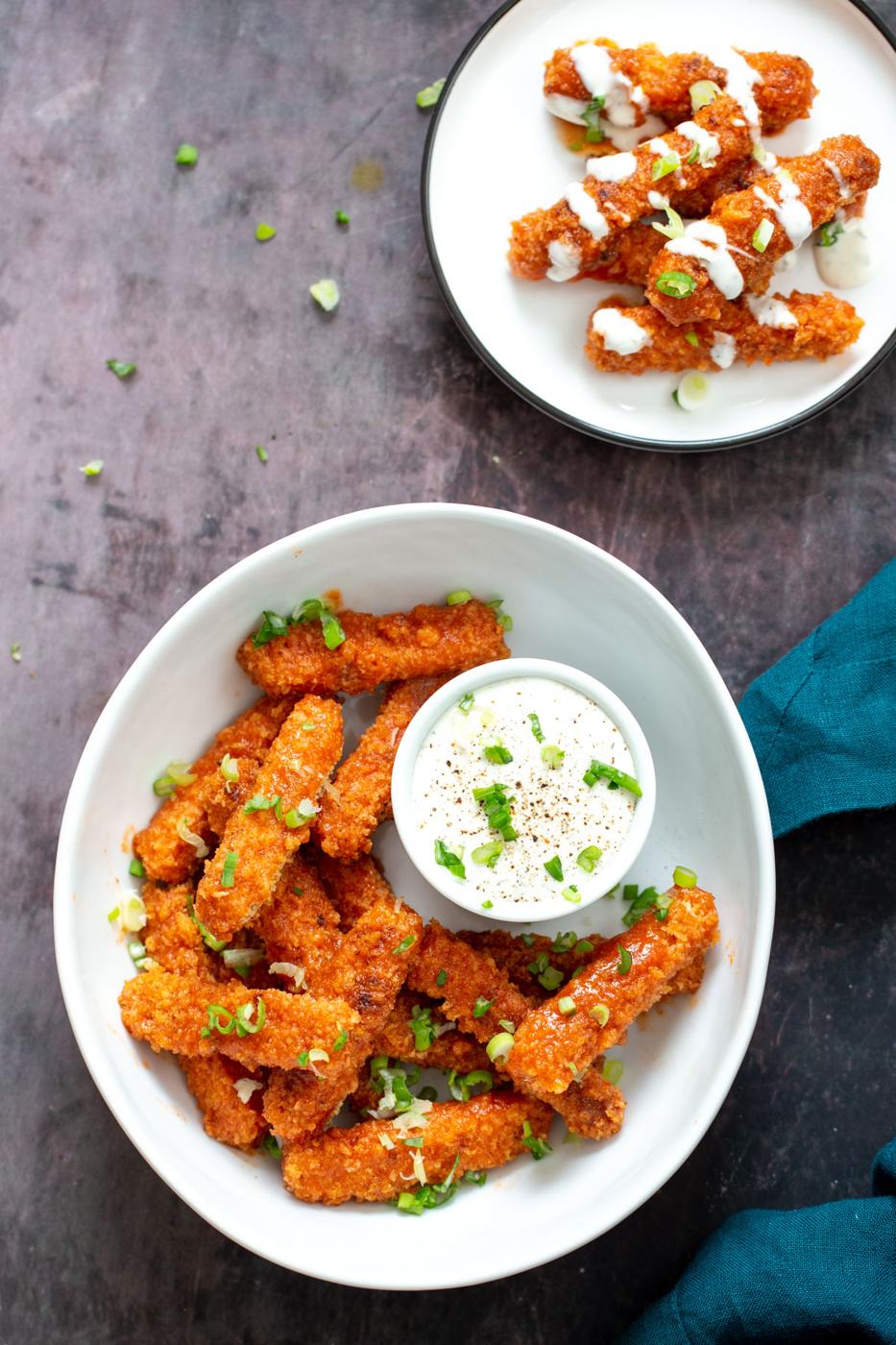 two plates with vegan baked firecracker tofu wings served with vegan ranch
