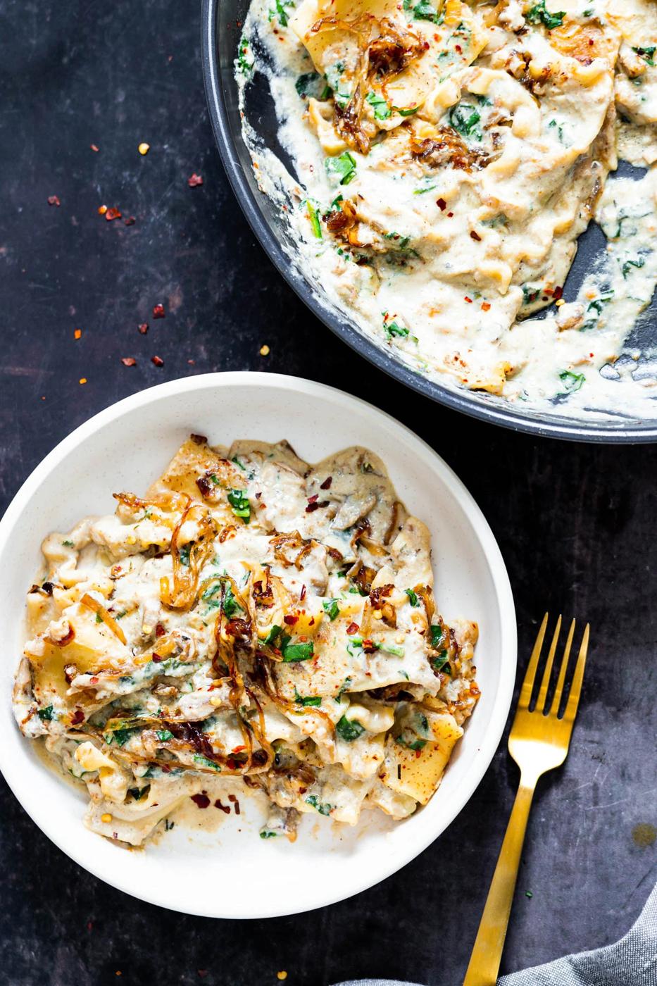 a white bowl with one skillet French Onion Lasagna with spinach and vegan bechamel