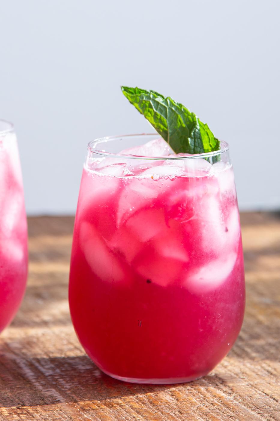 a glass of blueberry lemonade with a mint leaf