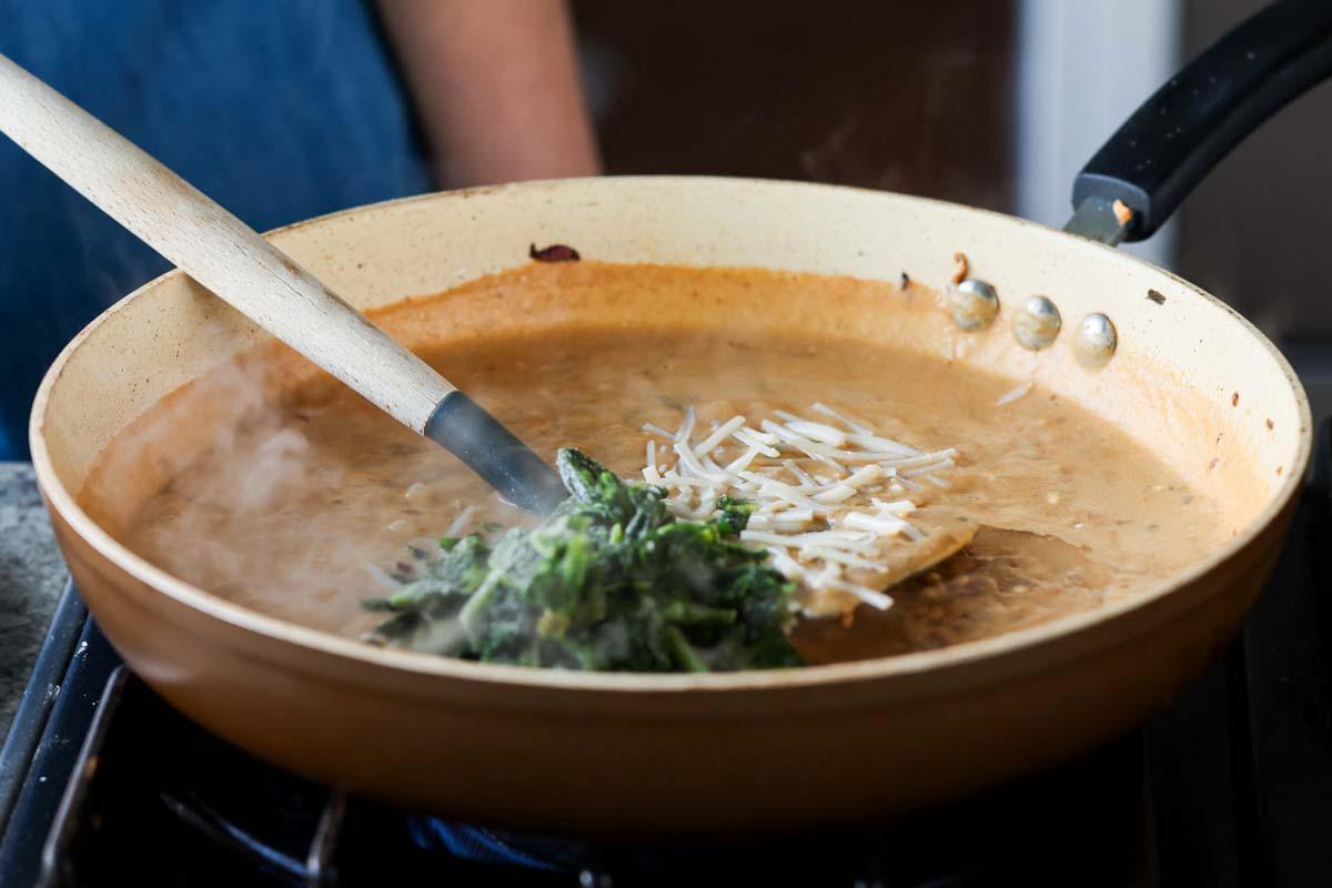 adding spinach and vegan cheese to the pan