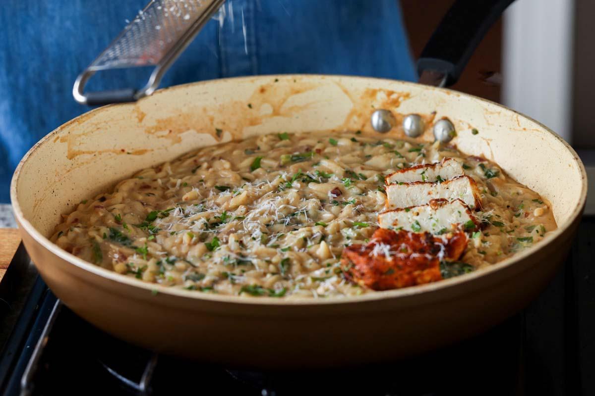 garlic parmesan orzo in the pan with the crispy tofu