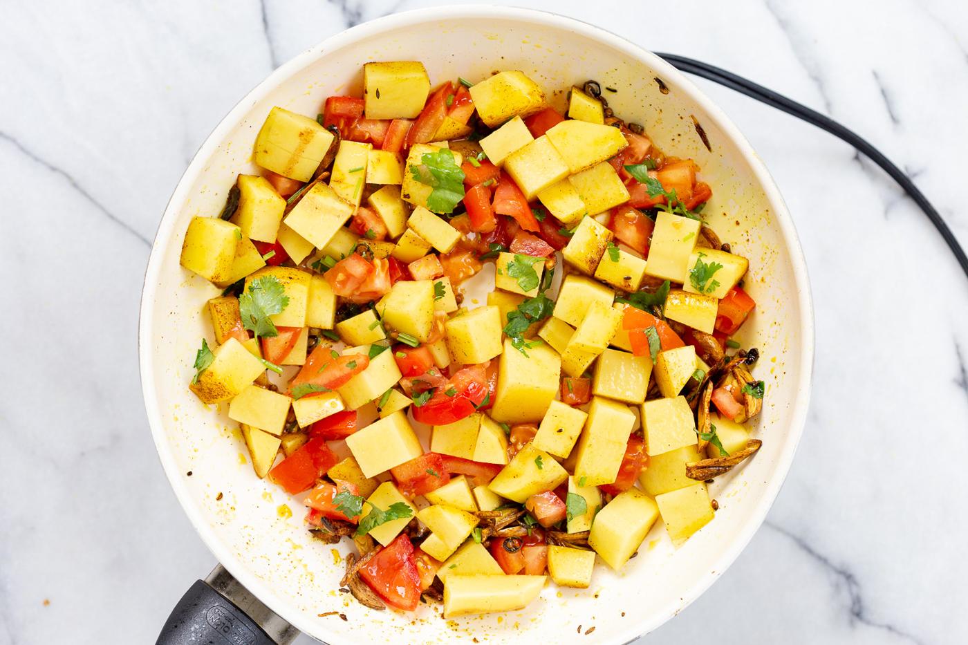Potatoes and tomatoes in white skillet