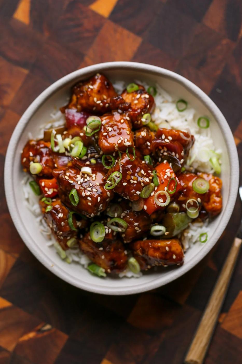 General Tso's tofu in a bowl with green onion and sesame seeds
