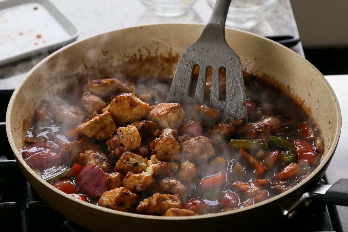 adding crispy tofu back to the pan of General Tso's sauce